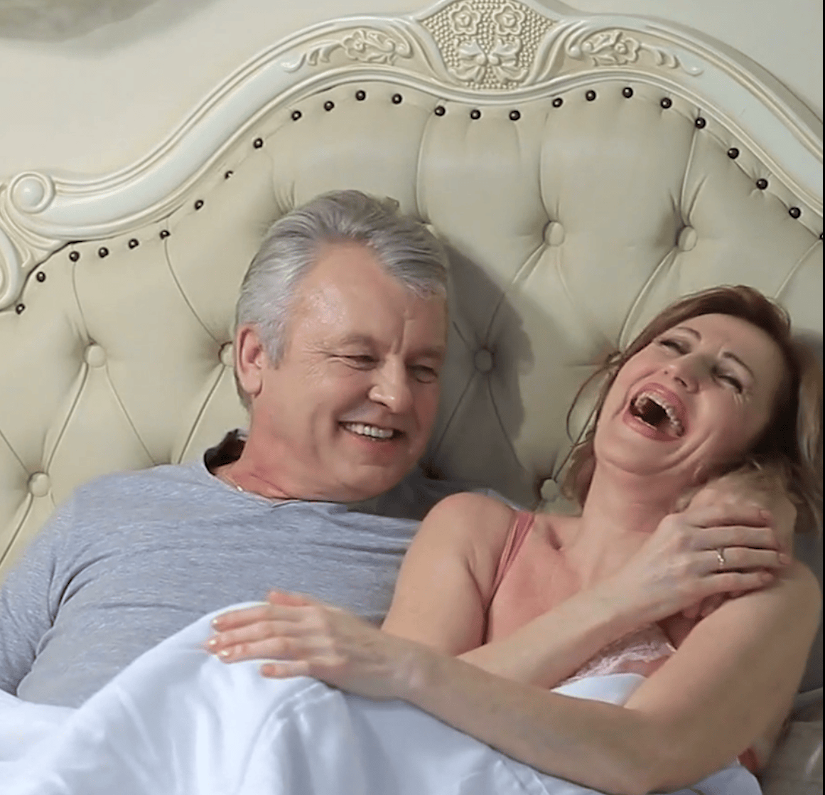Happy couple in bed, symbolizing the regained joy and intimacy possible through Overflow Health's Erectile Dysfunction solutions
